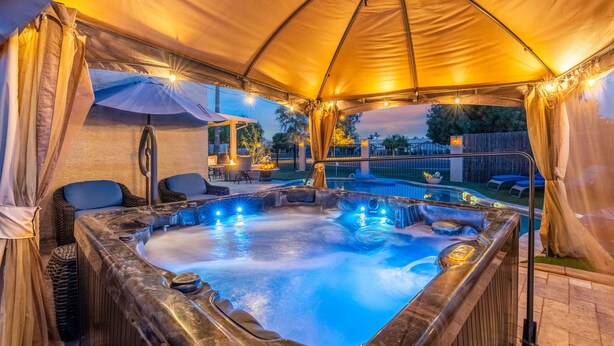 A hot tub under a canopy with a pool and outdoor furniture. - Private Guest Suite - Pool, Hot Tub, Cabana, Courtyard & Putting Green (Peoria)