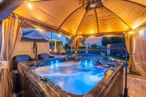 Boblebad under et halvtag med en pool og udendørs møbler.