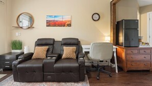 A living room with a recliner, a desk, a refrigerator, a clock, and a wall-mounted mirror. - Private Guest Suite - Pool, Hot Tub, Cabana, Courtyard & Putting Green (Peoria)