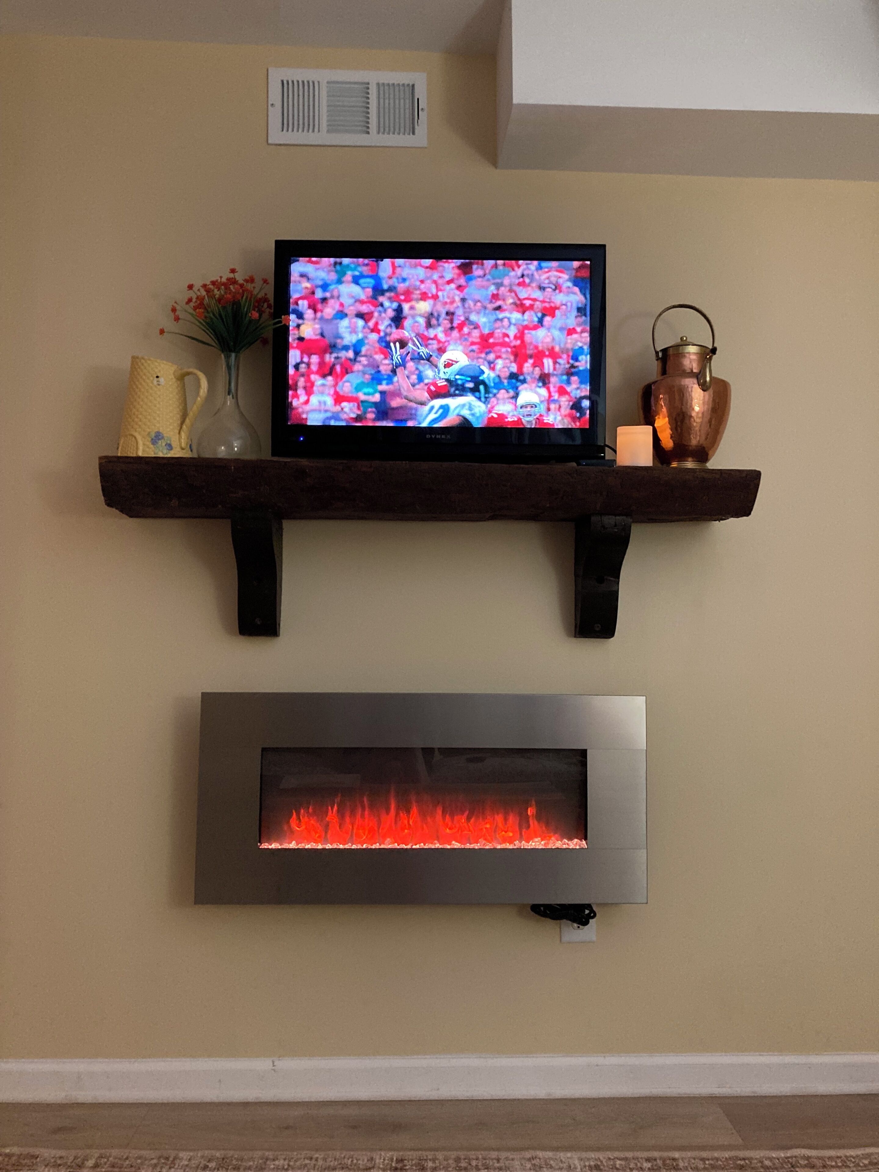 A television mounted on a wooden shelf above a fireplace.