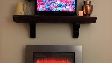 A television mounted on a wooden shelf above a fireplace.