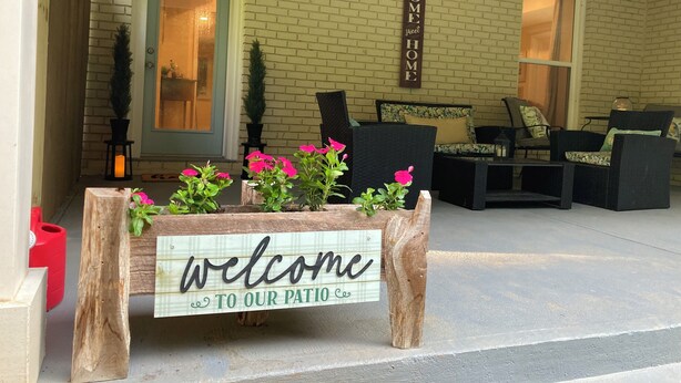 Een verwelkomend bord met daarop 'welkom op ons terras' en een bord met 'thuiskomen' voor een huis met bakstenen gevel.