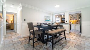 A dining area with a dark wooden table and chairs, a bench, and a window with blinds. - Pool + Tennis/B-Ball Courts + Game Room + Mins to Disney! (Kissimmee)