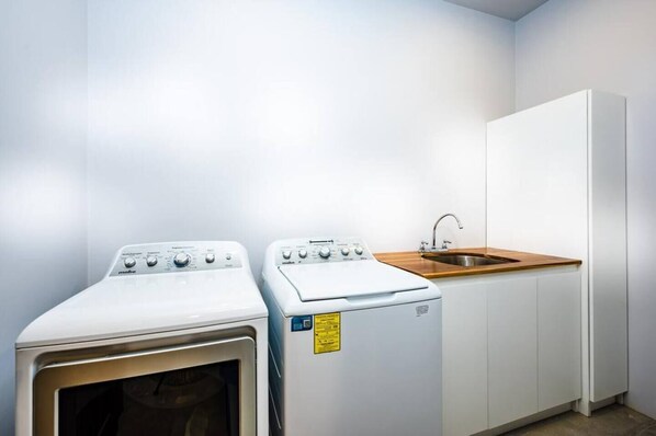 A laundry room with two front-loading washing machines and a sink.