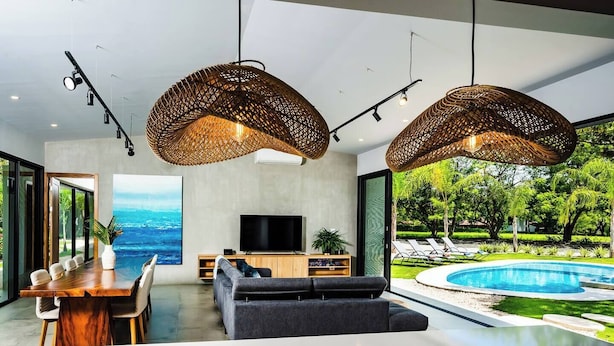 A modern living room with a dining area, a TV, and a poolside view. - Luxury Modern Escape in Hacienda Pinilla: Beach Club Access & Endless Adventure! (Pinilla)