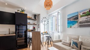 A modern kitchen with black cabinets, a wooden island, and a large wall clock. - PEARL AP4444 By Riviera Holiday Homes (Villefranche-sur-Mer)