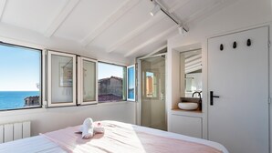 A bedroom with a bed, a window with a view of the sea, a bathroom with a sink, and a door with a mirror. - PEARL AP4444 By Riviera Holiday Homes (Villefranche-sur-Mer)