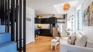 A modern kitchen with dark cabinets, a white countertop, and a hanging light fixture. - PEARL AP4444 By Riviera Holiday Homes (Villefranche-sur-Mer)