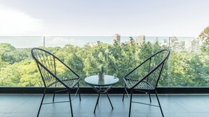A balcony with two chairs and a table, overlooking a cityscape and greenery. - MOT MANSION BOTANICAL (Buenos Aires)