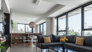 A modern living room with a sofa, coffee table, and a view of the city through large windows. - MOT MANSION BOTANICAL (Buenos Aires)