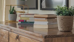 A wooden dresser with a plant, books, and framed pictures on top. - MOT MANSION BOTANICAL (Buenos Aires)