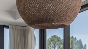 A round dining table with a white tablecloth, a woven pendant light, and three silver apples on a tray. - MOT MANSION BOTANICAL (Buenos Aires)