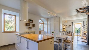 Een moderne keuken met een centraal eiland, witte kasten en een eethoek met een tafel en stoelen.