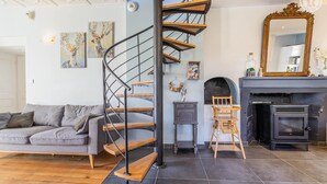 Een moderne woonkamer met een spiltrap, een open haard en een bank.