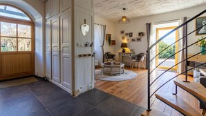 Een ruime woonkamer met houten vloer, een ronde salontafel en een trap naar een hoger niveau.