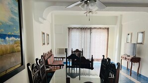 Een eetkamer met een ronde tafel, stoelen en een plafondventilator.