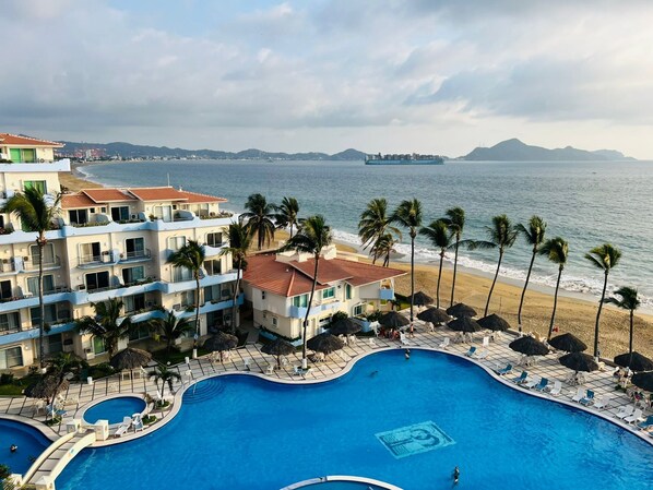 Ett semesterhotell med en stor pool, utsikt över stranden och flera balkonger.