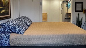 Ein Schlafzimmer mit einem Bett, einem Bild an der Wand und einer hängenden Pflanze.