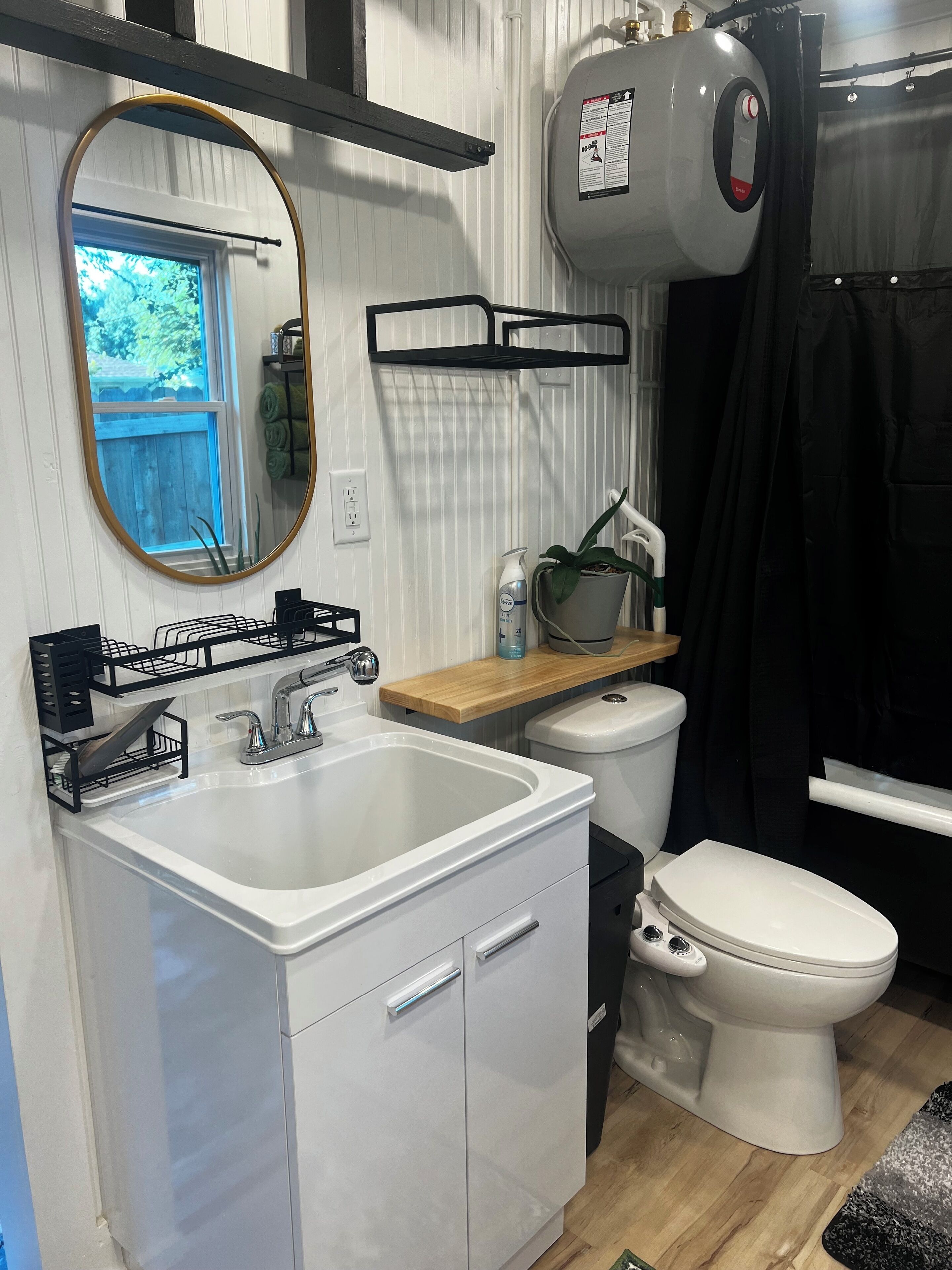 A compact bathroom with a white sink, a toilet, and a shower area.