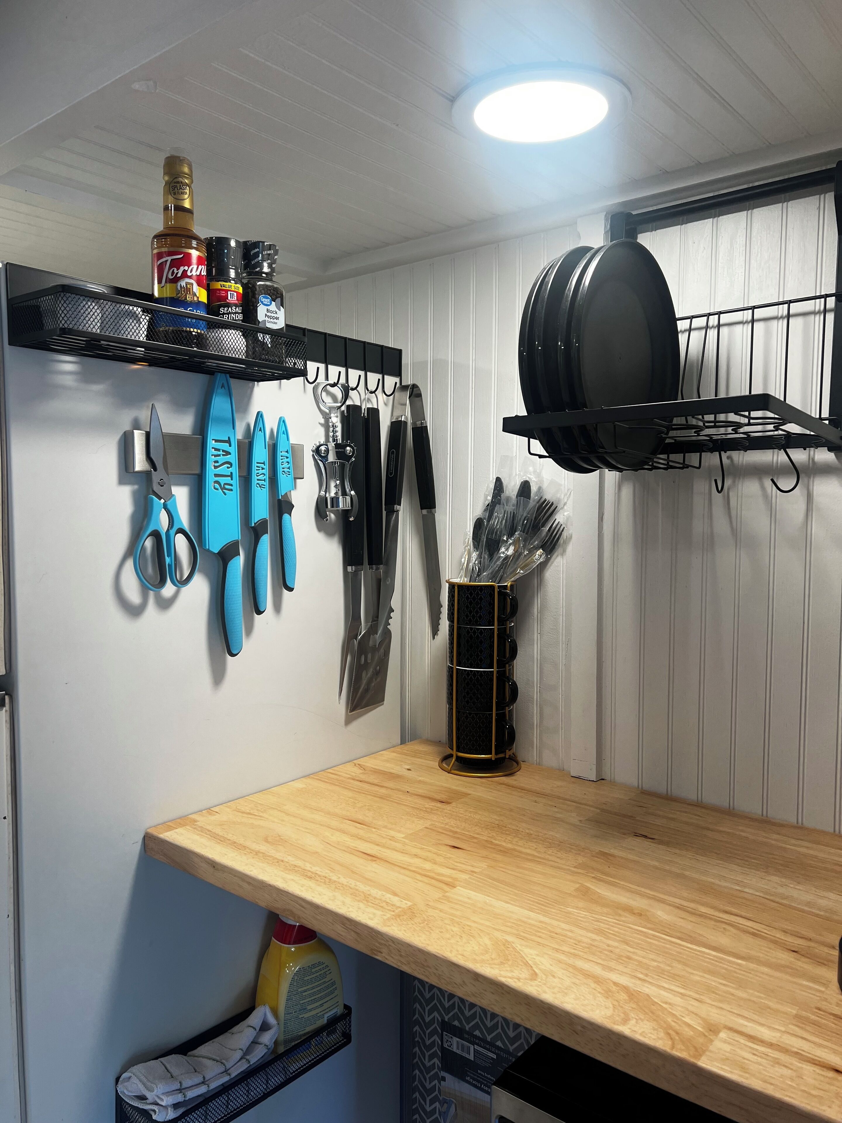 A kitchen with a wooden countertop, hanging kitchen tools, and a black pot rack.