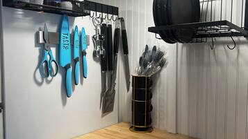 A kitchen with a wooden countertop, hanging kitchen tools, and a black pot rack.