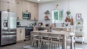 A modern kitchen with wooden cabinets, stainless steel appliances, and a central island with chairs. - Romantic Farm House (Springfield)