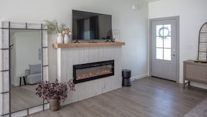 A modern living room with a fireplace, a large mirror, and a television mounted above it. - Romantic Farm House (Springfield)