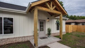 A house with a covered porch, a brick foundation, and a wooden fence in the background. - Romantic Farm House (Springfield)