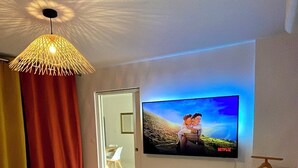 Un dormitorio moderno con una cama grande, un televisor de pantalla plana montado en la pared y una lámpara de techo original.