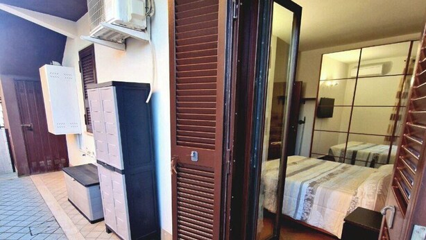 A room with a bed, a wardrobe, and a sliding door leading to another room. - Apartment 5 min from Airport, Self Check-in h24, Private Garden, Wi-Fi, A/C, TV (Rome Fiumicino)