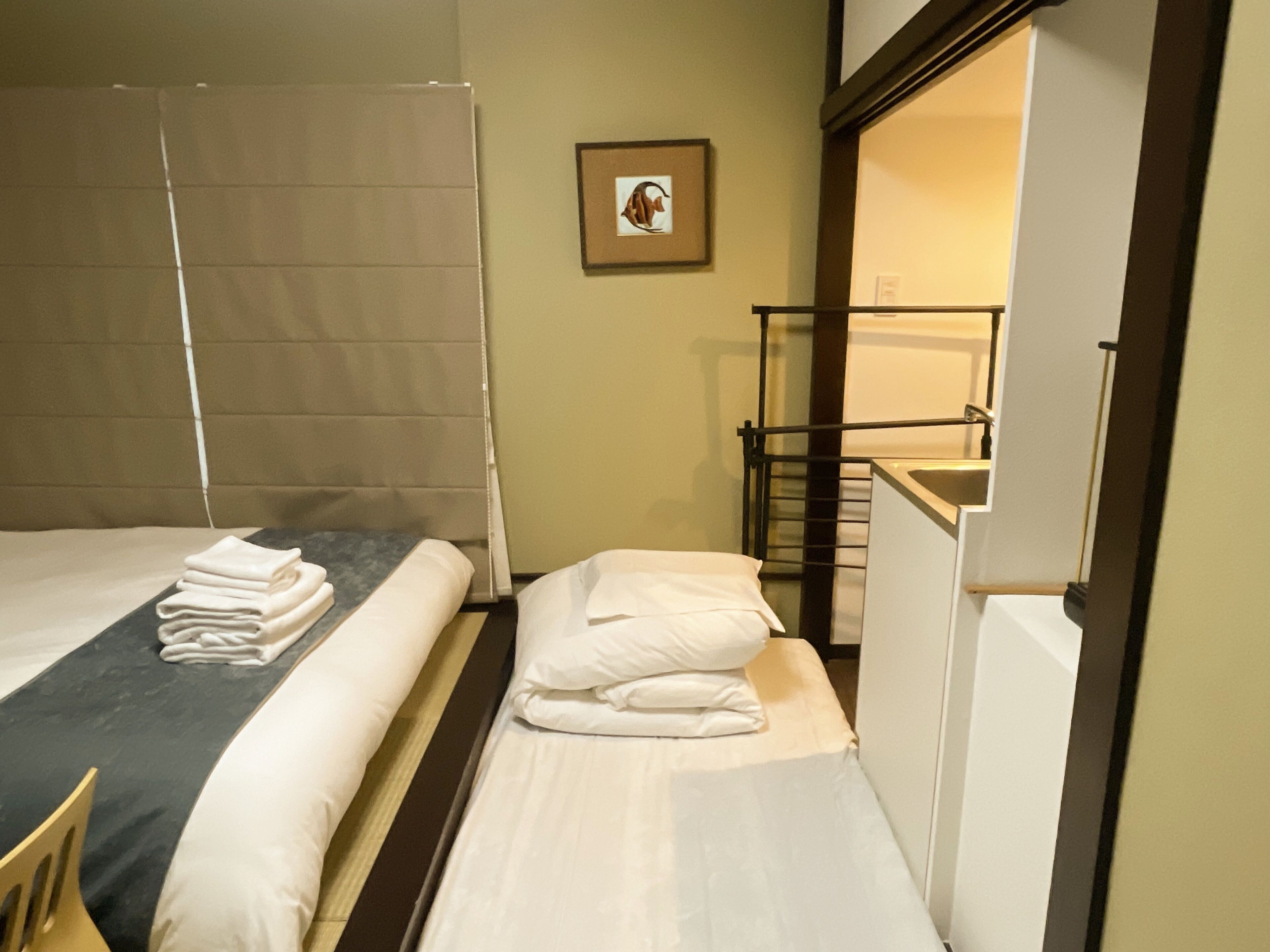 Une chambre d’hôtel avec deux lits, une petite table, un tableau encadré au mur et un escalier menant à un étage supérieur.