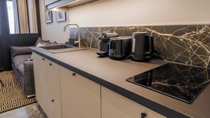 A modern kitchen with a black countertop, a built-in stove, and a coffee maker. - Wonderful Apartment 1br4p (Paris)
