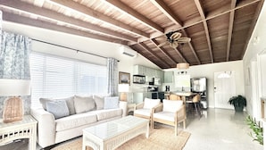 A spacious living area with a high ceiling, a sofa, a coffee table, and a dining area with chairs. - SC3- Southern Comfort Three at 240 11th St. KCB. Private Pool, Dock & Tiki Bar. (Key Colony Beach)