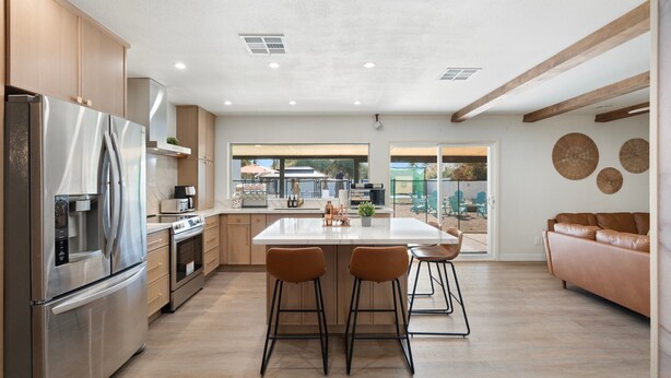 Una cucina moderna con elettrodomestici in acciaio inossidabile, mobili in legno e un'isola centrale con sgabelli da bar.