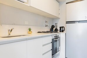 Departamento Deluxe, vista a la ciudad | Cocina privada | Refrigerador, horno, parrilla de estufa y utensilios de cocina 