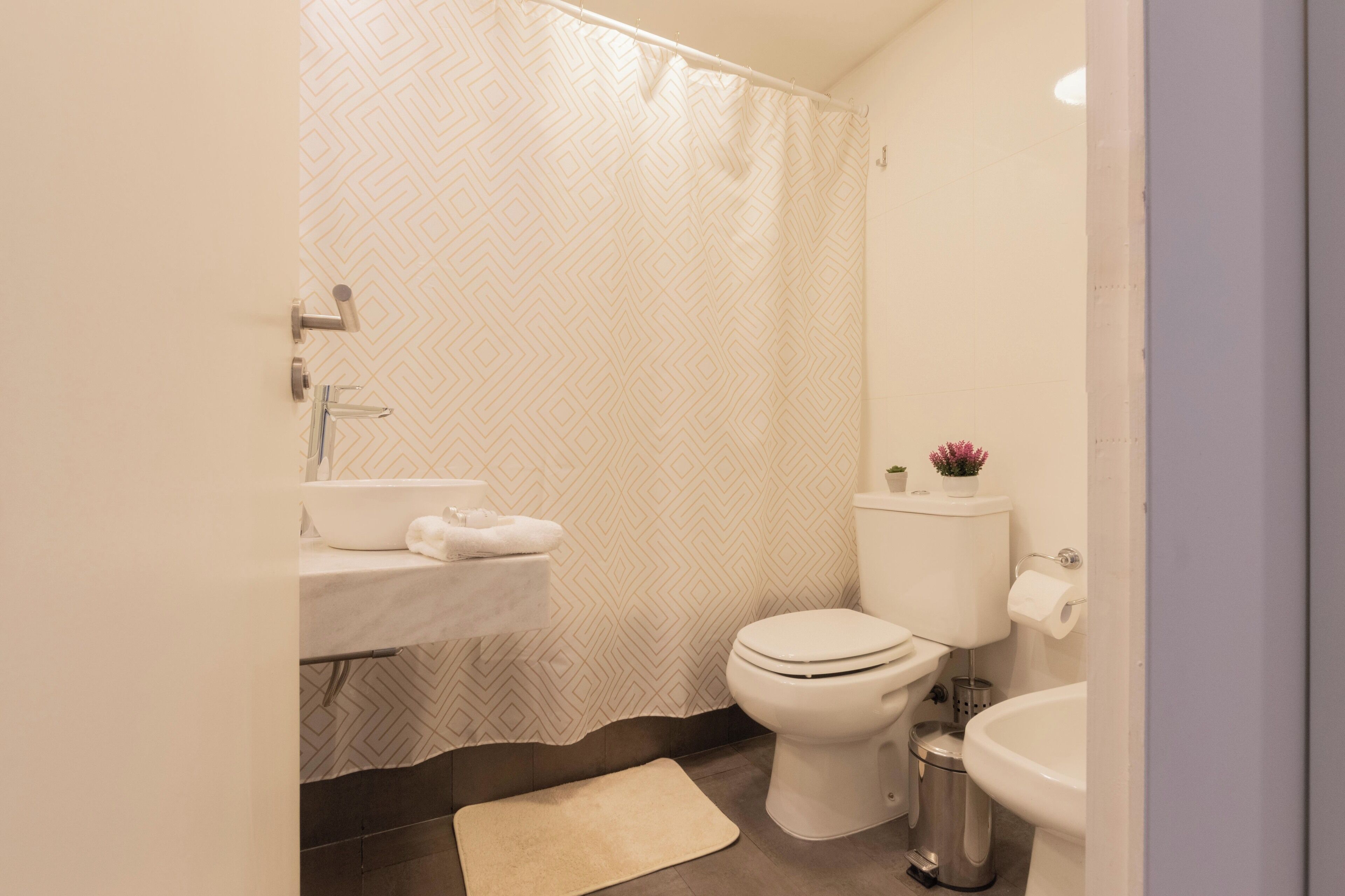 Un baño moderno con cortina de ducha, inodoro, lavabo y bidé.