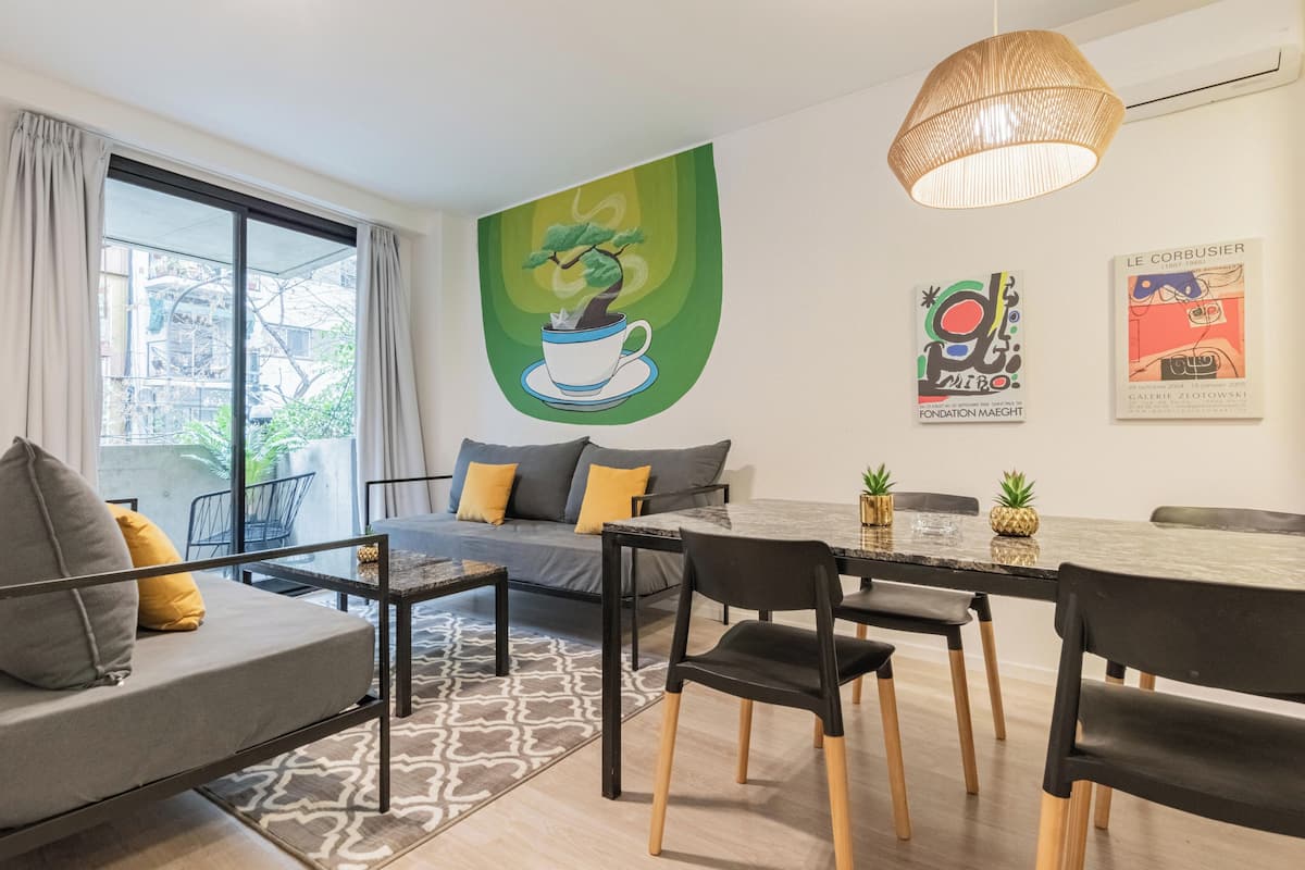 Una sala moderna con sofá, mesa de comedor, sillas y obras de arte en las paredes.