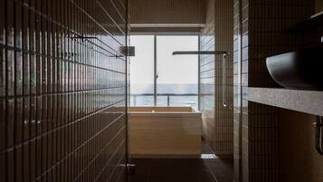 A modern bathroom with a large window, a wooden bathtub, and a sink.