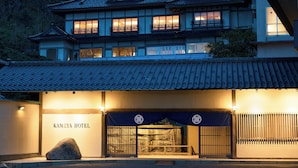 Un hotel tradizionale giapponese con tetto in tegole, numerose finestre e un cartello con su scritto "KAMEYA HOTEL".