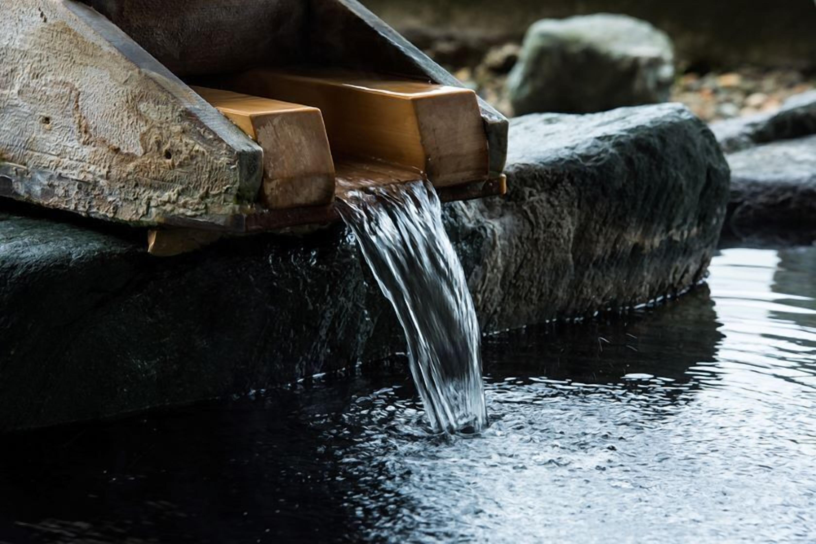 A water feature with a wooden structure and a stream flowing over rocks.