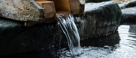 A water feature with a wooden structure and a stream flowing over rocks.