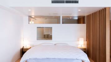 Een moderne hotelkamer met een groot bed, twee nachtkastjes, een spiegel en een wandpaneel van hout.