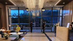 A modern lobby with a large reception desk, seating area, and a view of the outdoors.