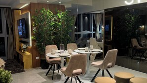 A modern dining area with round tables, cushioned chairs, and a large potted plant.