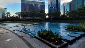 A modern urban pool area with a clear sky, surrounded by high-rise buildings.