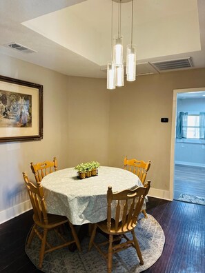 Enjoy meals in this dining area with a round table and six chairs, surrounded by pendant lights and a beautiful piece of artwork.