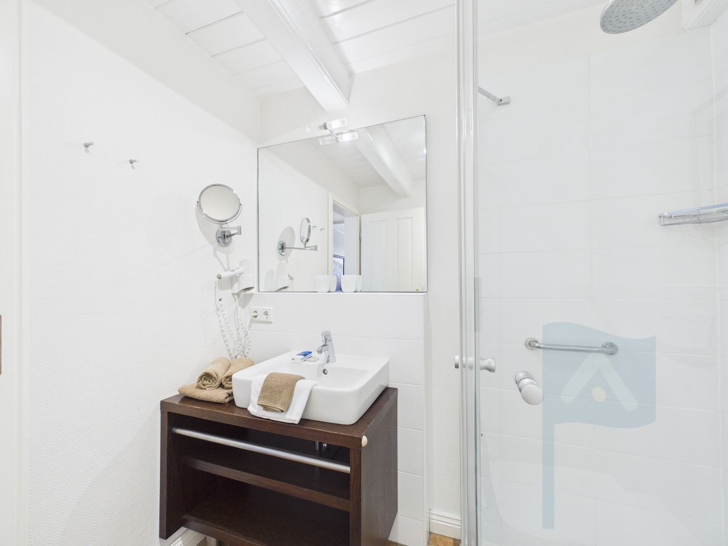 A modern bathroom with a glass shower enclosure, a white sink, and a mirror above it.