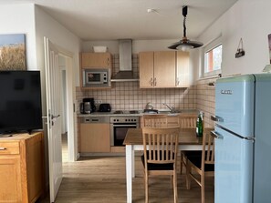 Una cocina compacta con armarios de madera, microondas, estufa, pileta y refrigerador.