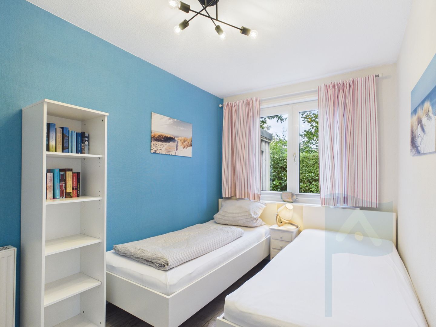 Una stanza con un letto, un comodino, una libreria, una finestra con tende e una lampada a soffitto.