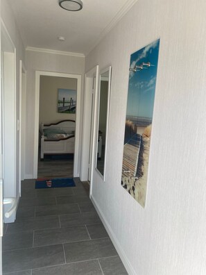 A hallway with a bed, a painting, and a door leading to another room. - Here you go on vacation near the beach and the city - Haus Carstensen (Wyk auf Föhr)